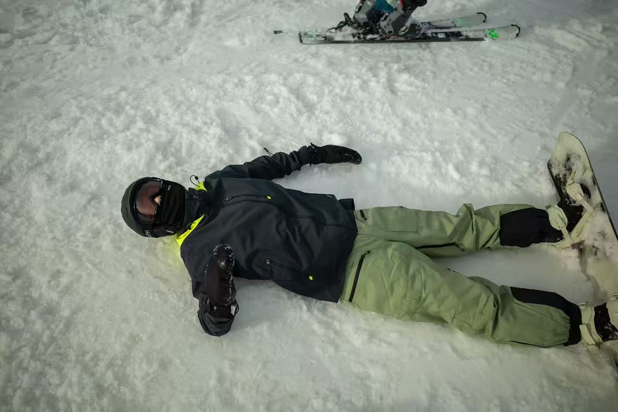 Forest Wu resting in the snow while snowboarding